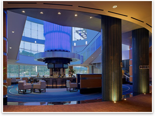 An 86-foot-high glass cylinder called the Drum sits above a bar inside a glass lounge. The Drum has an illuminating blue light that dances to make subtle reference to the river. The Drum serves as a vertical element tying the two floors together. Photo courtesy of Bergman Walls & Associates.
